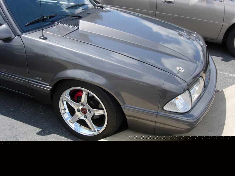 Front quarter of a gray Fox-body Mustang with chrome wheels