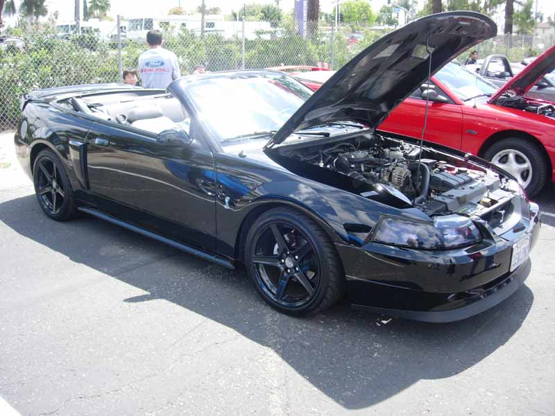 Black New Edge Ford Mustang convertible with hood up at a show
