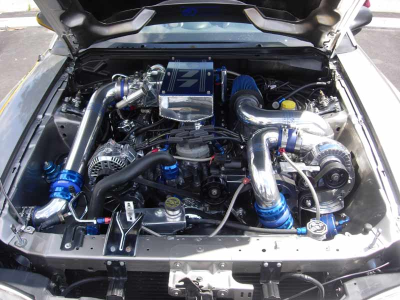 Heavily modified twin-turbo engine bay with blue piping