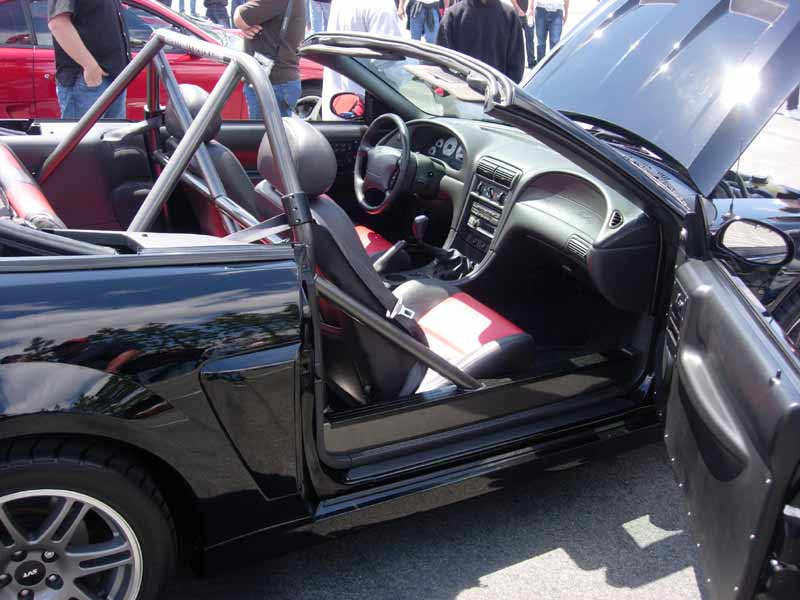 Black Mustang convertible interior with roll bar and red seats