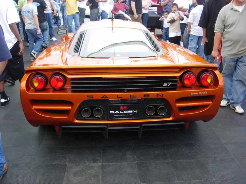 Rear of an orange Saleen S7 supercar surrounded by a crowd