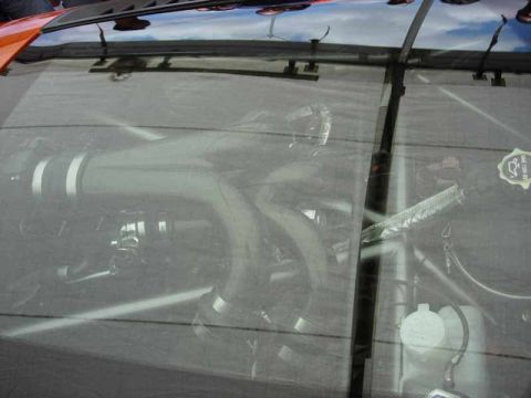 1998 Ford Crown Victoria - modified engine and piping seen through a tinted transparent hood or window panel, with sky reflections.