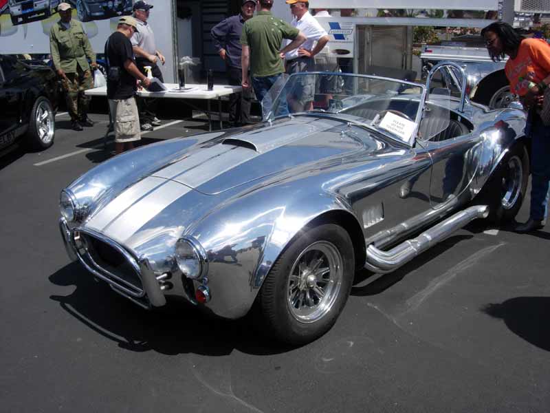 Polished bare-aluminum Shelby Cobra roadster at a car show