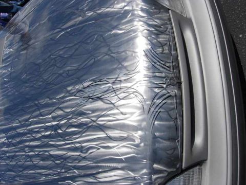 1998 Ford Crown Victoria - close-up shows a silver car hood covered in swirled engine-turned metal finish accented with fine black pinstriping.