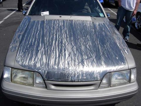 1998 Ford Crown Victoria - front of a silver car shows a hood decorated with swirled engine-turned metalwork and black flame pinstripe artwork.