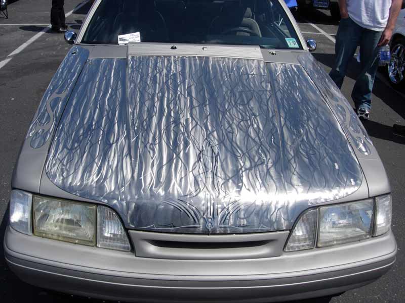 Front of silver car with engine-turned and flame pinstriped hood