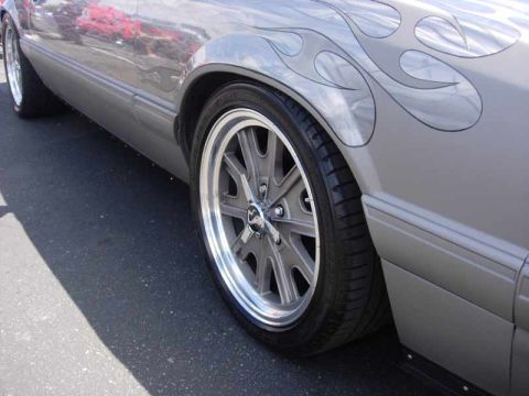 1998 Ford Crown Victoria - lowered gray car displays black flame graphics along its fender above a chrome and gray eight-spoke wheel.