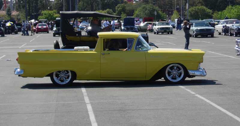 Yellow 1957 Ford Ranchero custom in profile at car-show lot