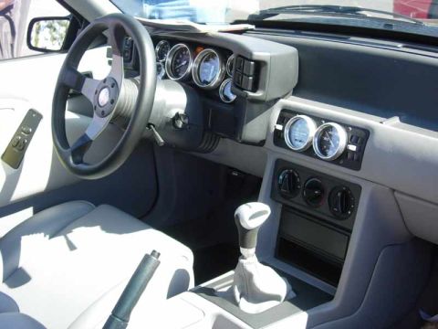 1998 Ford Crown Victoria - Interior of a sports coupe showing a three-spoke steering wheel, round gauges, dual auxiliary gauges and a leather-booted manual shifter.