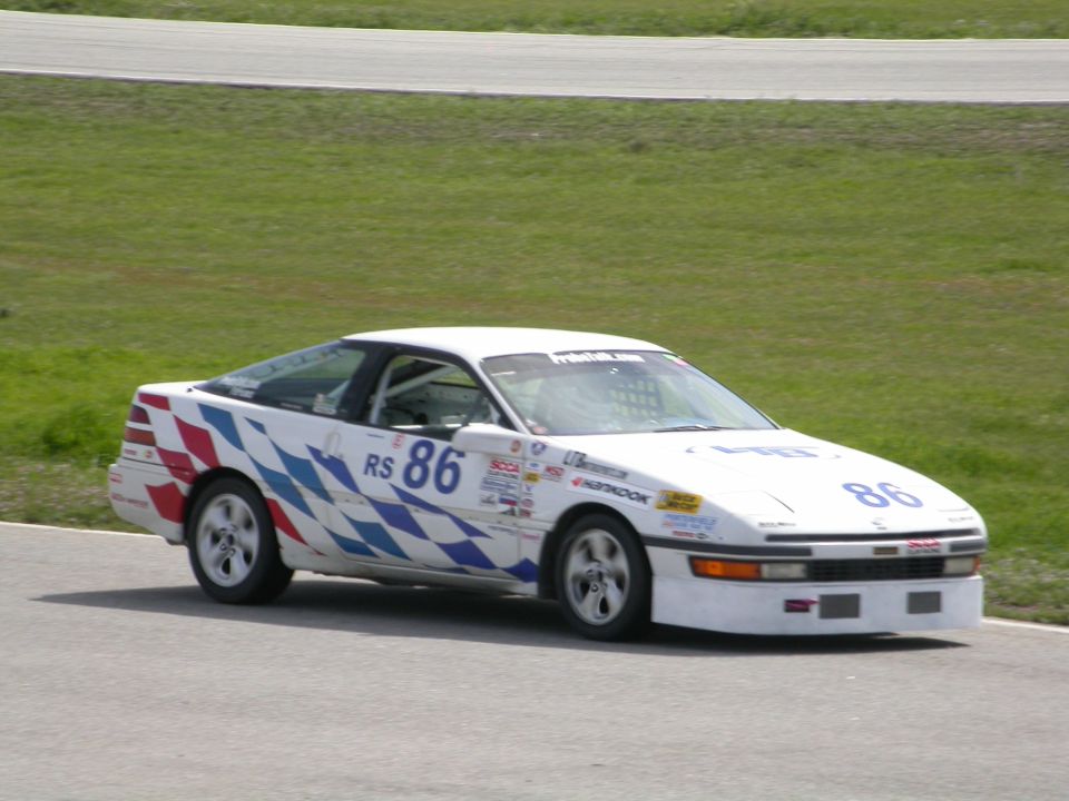 White race car with checkered graphics and number 86 on track
