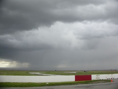 1990 Ford Probe - Stormy weather approaches a racetrack, with dark clouds dominating the sky.