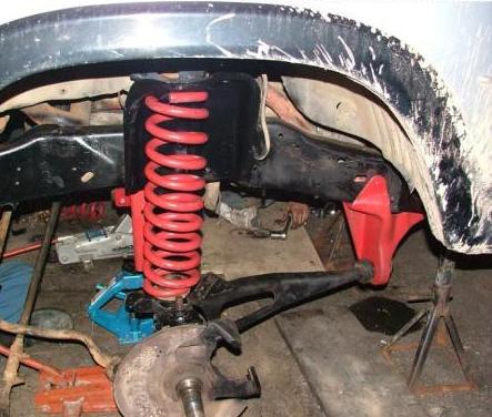1985 Ford Bronco - Vehicle suspension components are visible during a repair process, supported by jacks and stands.