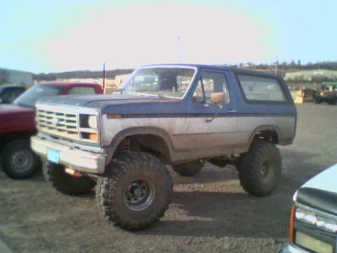 1985 Ford Bronco - This 1985 Ford Bronco features a two-tone blue and silver paint scheme and is equipped with oversized off-road tires.