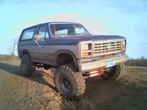 1985 Ford Bronco - Ford Bronco with large tires driving off-road on a sunny day.