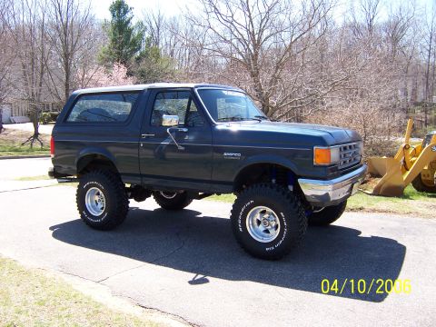 1987 Ford Bronco - This 1987 Ford Bronco is shown from a three-quarter front angle, modified with a lift kit and off-road tires.