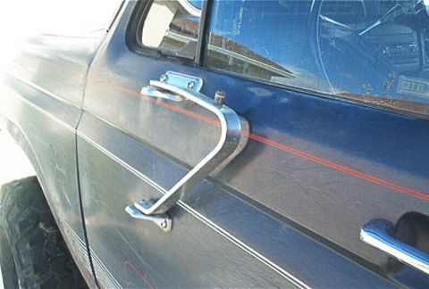 1986 Ford Bronco - Close-up of the side of a 1986 Ford Bronco, highlighting the door handle and distinctive pinstriping.