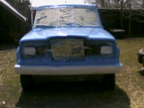 1978 Ford Bronco - Front view of a blue SUV with its windows taped, likely undergoing preparation for painting.