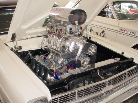 1972 Ford Ranchero - A highly modified engine with a prominent supercharger and air intake is displayed under the hood of a white car.