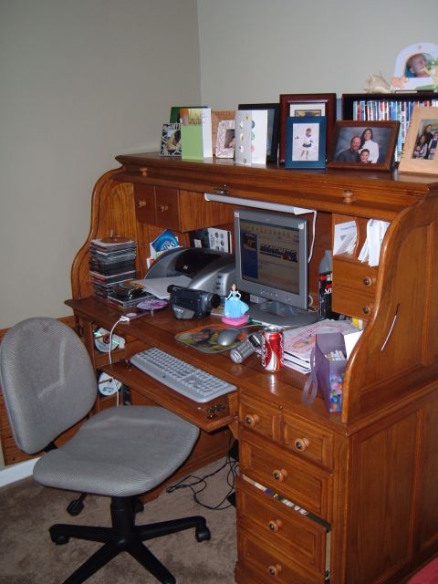 1971 Ford Ranchero - A cluttered wooden roll-top desk is set up with a computer, office supplies, and personal mementos.