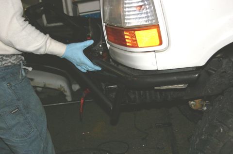1995 Ford Bronco - Close-up of a person installing a custom front bumper on a white SUV.
