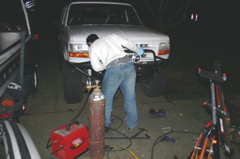 1995 Ford Bronco - Person welding a custom bumper onto a 1995 Ford Bronco at night.