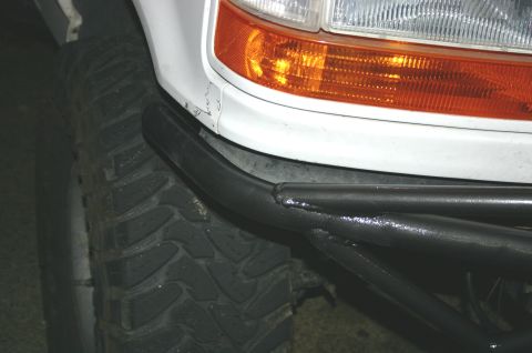 1995 Ford Bronco - Close-up of a 1995 Ford Bronco's front corner, a large tire and a custom tubular bumper.