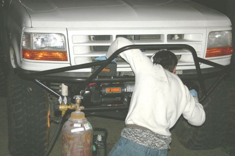 1995 Ford Bronco - Working on the front bumper of a 1995 Ford Bronco, with a winch and welding setup visible.