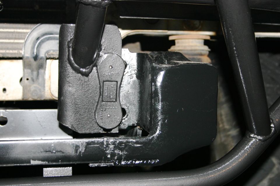 Close-up of a black tow hitch receiver attached to a vehicle frame, with part of the radiator visible