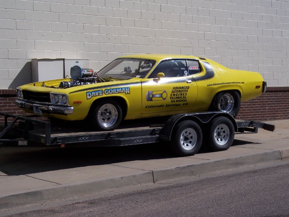 Yellow drag car with blower, Dave Gorman lettering, and Advanced Automotive Engines Technical School graphics, on a trailer