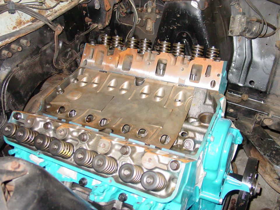 Teal V8 engine block out of vehicle with heads off showing valve springs and lifter valley