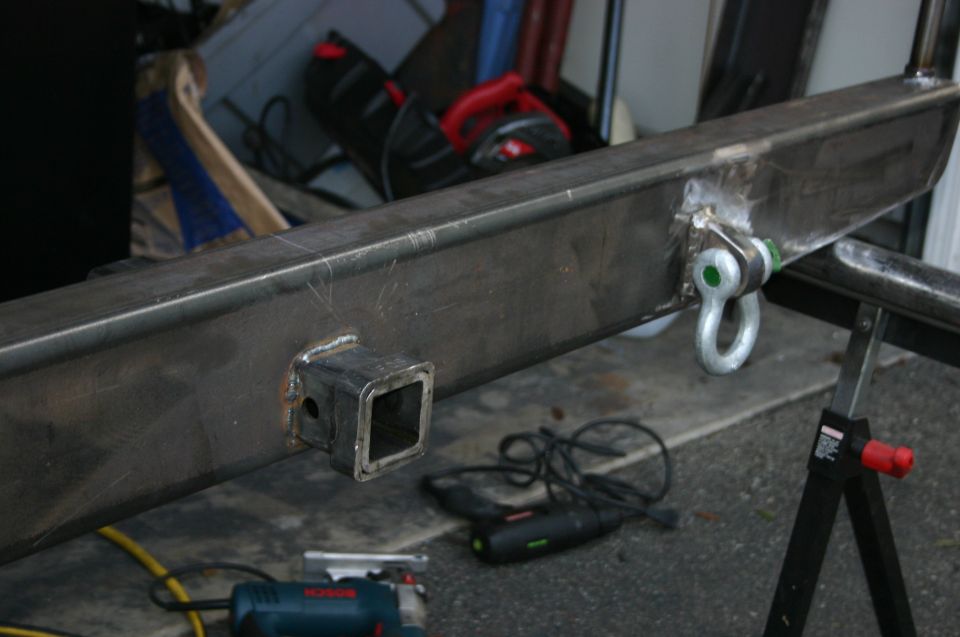 Steel bumper with a square hitch receiver and a D-ring tow hook, resting on sawhorses