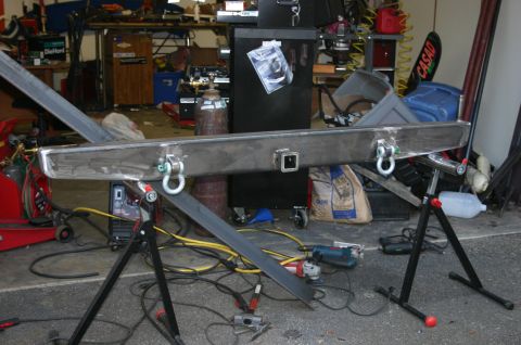 1995 Ford Bronco - Custom rear bumper assembly with tow hitch and D-rings, supported by stands in a workshop.