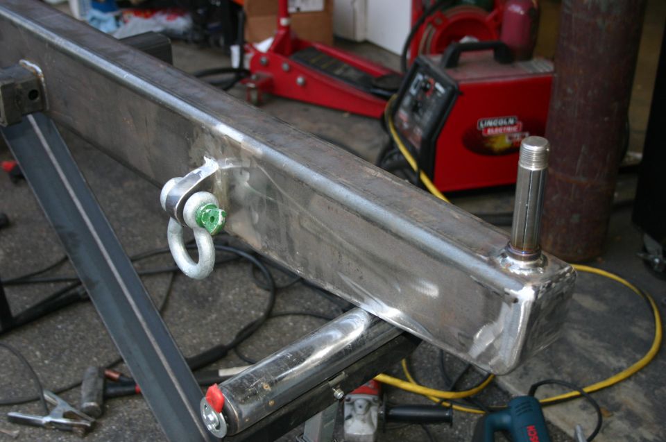 Fabricated steel rear bumper with D-ring shackle mount and receiver hitch pin. Welding equipment in background