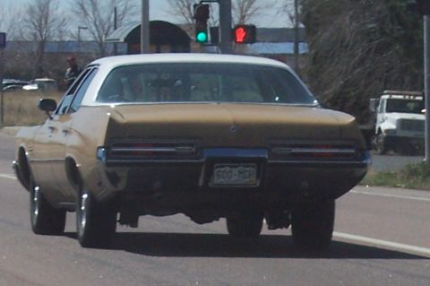 1972 Ford Ranchero - Rear view of a vintage station wagon driving on a road with a traffic light in the background.