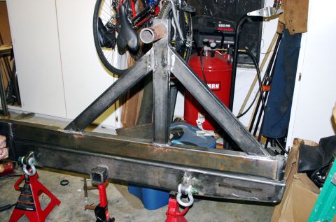 1995 Ford Bronco - A custom-built steel rear bumper and tire carrier assembly is shown in a workshop setting, supported by jack stands.
