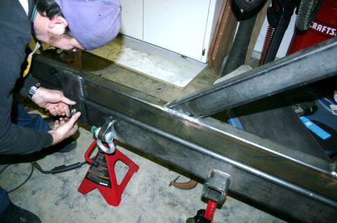 1995 Ford Bronco - A person works on fabricating a custom rear bumper with integrated tow hitch receiver and shackle mounts.
