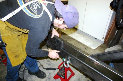 1995 Ford Bronco - Man welding a custom metal frame, possibly for a vehicle bumper or carrier.