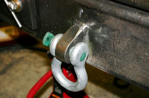 1995 Ford Bronco - A close-up view of a tow hitch shackle mount attached to a vehicle's bumper, a green pin.