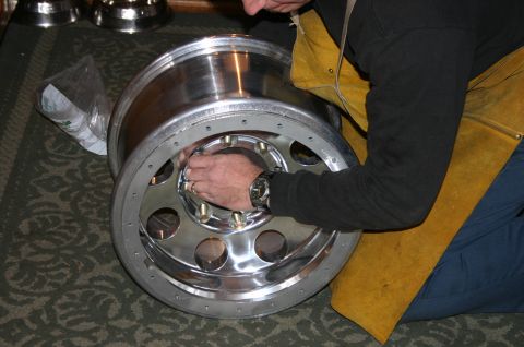 1995 Ford Bronco - A person's hands are shown working on a shiny chrome wheel, with a yellow apron visible.