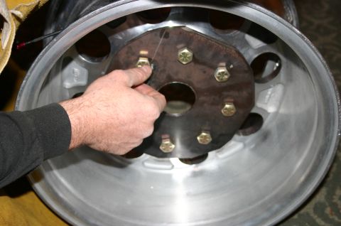 1995 Ford Bronco - A person is shown installing an adapter plate onto a vehicle wheel rim.