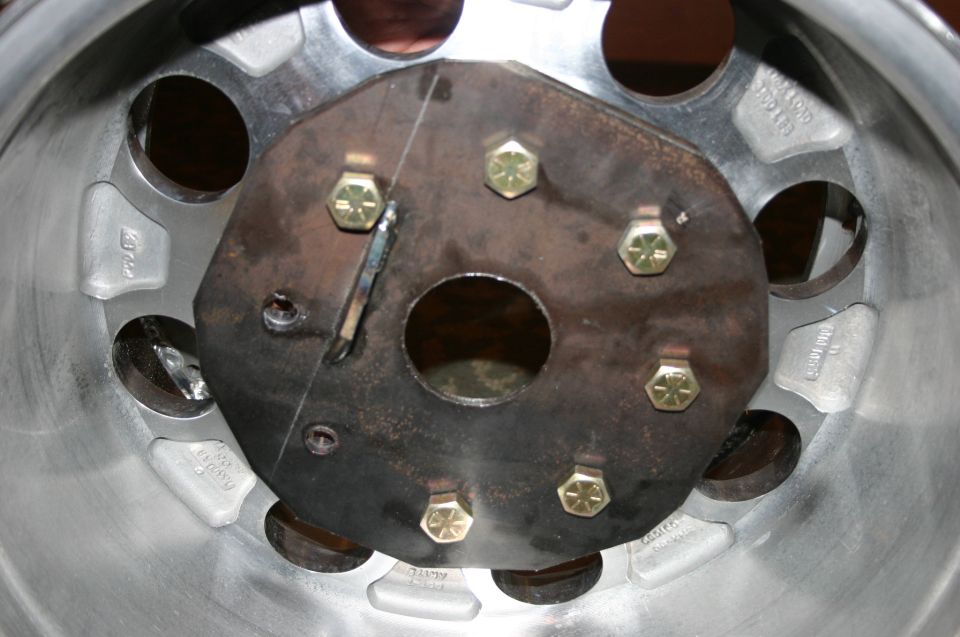Close-up of a metal wheel hub with six bolts and a central circular opening