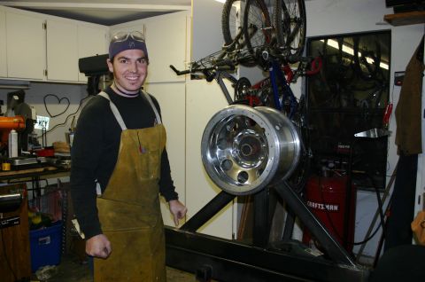 1995 Ford Bronco - A man stands in a workshop next to a large chrome tire rim, with bicycles mounted on the wall.