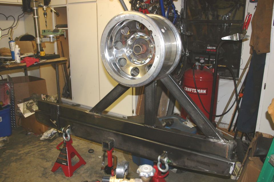 Metal tire carrier and bumper assembly with a chrome wheel mounted on a stand