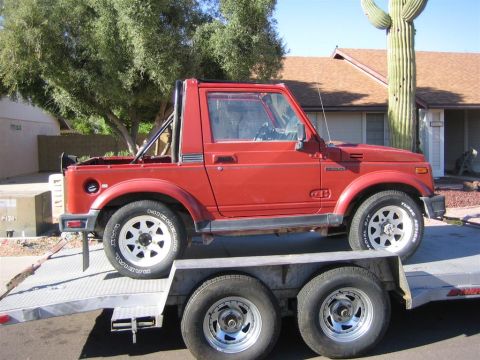 1987 Suzuki Samurai - A red Suzuki Samurai is loaded onto a flatbed trailer, viewed from the side.