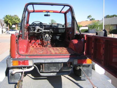 1987 Suzuki Samurai - This red Suzuki Samurai is missing its interior components and appears to be on a trailer.