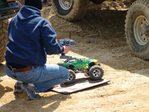 1994 Ford Bronco - A person operates a remote-controlled monster truck near the tires of a much larger vehicle.
