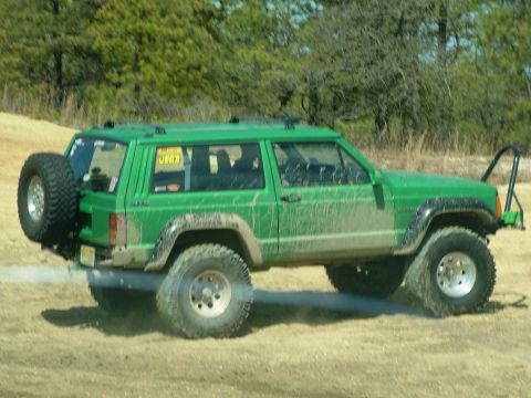 1994 Ford Bronco - This lifted green Jeep Cherokee XJ is equipped for off-road adventures with a rear-mounted spare tire and tires.
