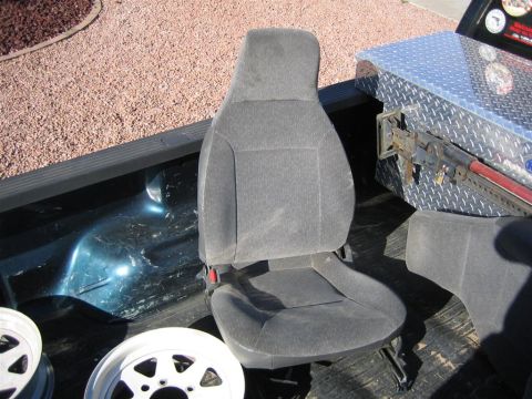 1987 Suzuki Samurai - A vehicle seat and spare tires are stored in the bed of a pickup truck next to a toolbox.