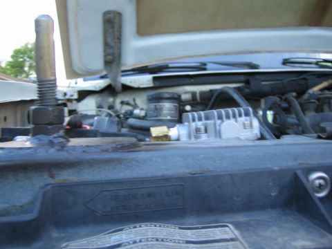 1990 Ford Bronco - Under-hood view near a radiator support shows wiper arms, components and a French-English Attention warning label.
