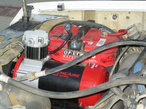 1990 Ford Bronco - engine bay shows red Optima batteries mounted above a black ExtremeAire High Output air compressor with routed hoses.